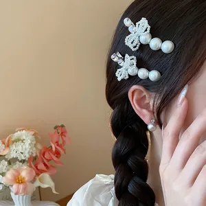 Close-up of elegant French style pearl hair clips with rhinestone bow on braided hair.