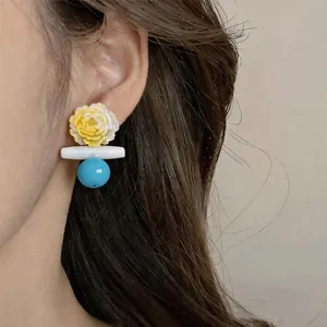 Nahaufnahme eines handgefertigten Blumenohrrings mit türkisfarbener Perle