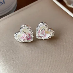 Vista dettagliata di orecchini a cuore in argento con intarsio di farfalla rosa