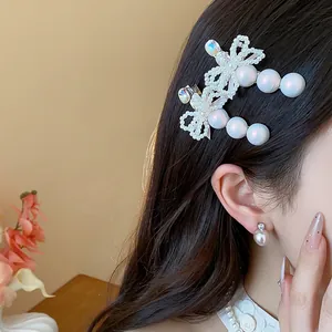 Detail of elegant pearl bow hair clip with rhinestones worn on hair for a French look.