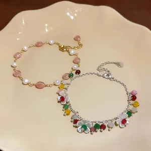 Dettaglio di braccialetti in oro 14k e argento con perle colorate e ciondoli a fiore