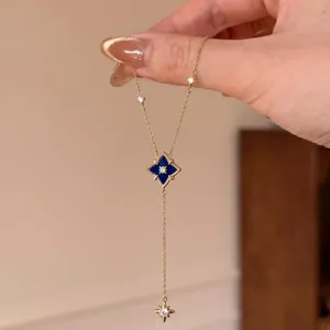 Nahaufnahme einer eleganten Goldkette mit blauem Rauten- und Stern-Zirkonia-Anhänger