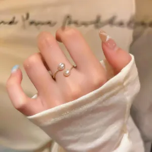 Primo piano di un elegante anello aperto con doppia perla placcata oro 14 carati al dito