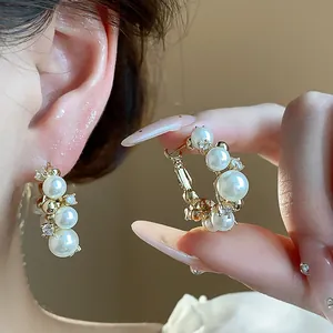 Détail de boucles d'oreilles créoles en perles plaquées or 14 carats avec zircons