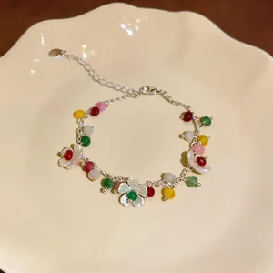 Elegante bracciale di perline colorate con ciondoli a fiore bianco su un piatto di ceramica