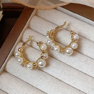 Vue détaillée d'élégantes boucles d'oreilles dorées 14 carats avec perles et zircons.