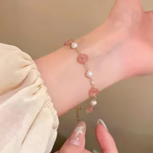 Vista dettagliata di un bracciale di perle con perle rosa e catena dorata sul polso