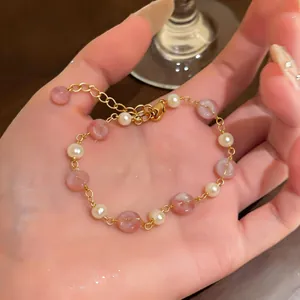 Dettaglio del bracciale di perle placcato oro 14k con perline rosa tenuto in una mano