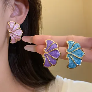 Vintage floral enamel stud earrings in pink, purple and blue shown on ear and hand.