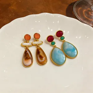 Primer plano de pendientes vintage de resina en forma de gota en dos colores en un plato