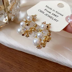 Détail macro de boucles d'oreilles élégantes en or 14 carats avec perles et zircons.
