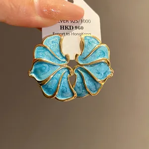 Macro detail of vintage blue enamel flower earrings with elegant gold plated edges