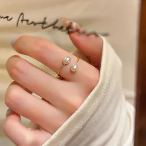 Dettaglio di un anello regolabile placcato oro 14k con due eleganti perle bianche.