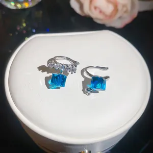 Close-up detail of sparkling blue cube zircon ear cuffs on white jewelry box stand