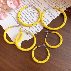 Detailed view of yellow polka dot C-shaped hoop earrings featuring silver needles