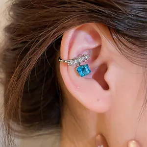 Close-up of a sparkling blue zircon sugar cube ear cuff on an ear, non-pierced jewelry.