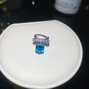 Detailed view of silver ear cuff with blue square cubic zirconia and white stones