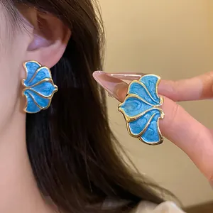 Close-up of vintage blue enamel flower stud earrings with gold-tone edges on a model