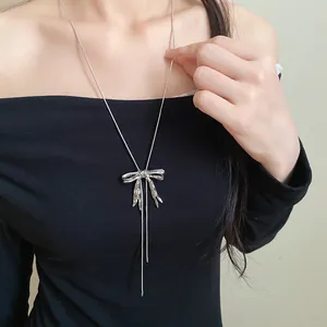 Detailaufnahme einer silbernen Halskette mit Schleifenanhänger und langen Quasten.