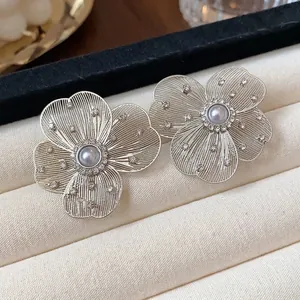 Elegant hollowed-out flower stud earrings with pearl and rhinestone accents in silver tone
