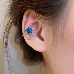 Detailed close-up showing a shiny blue square zircon ear cuff with small flower dangle