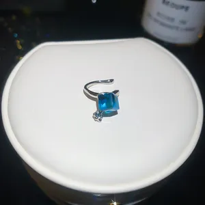 Macro detail showing a sparkly blue square zircon ear cuff on a white jewelry stand