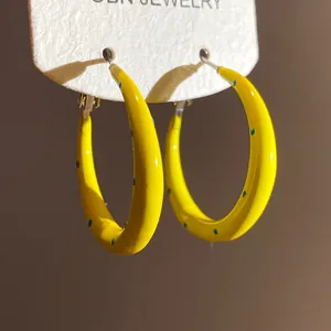 Close-up detail of yellow C-shaped hoop earrings with green polka dots on display card