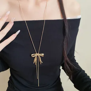 Detailansicht der goldenen Halskette mit gefaltetem Schleifenanhänger und Quasten.