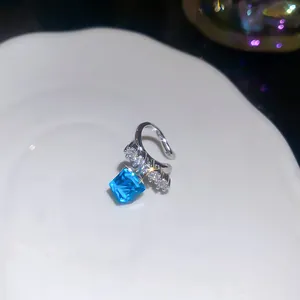 Close-up of elegant silver ear cuff with sparkling blue square zircon and clear stones