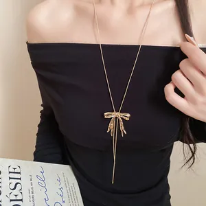 Detailansicht einer goldenen Halskette mit zerknittertem Schleifenanhänger