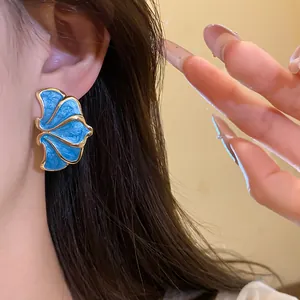 Close-up of blue enamel flower earrings with gold finish and vintage palace style design.
