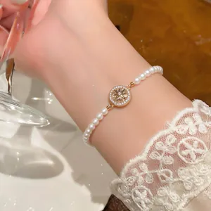 Détail d'un élégant bracelet de perles blanches avec un pendentif étoile à huit branches