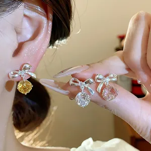 Dettaglio di eleganti orecchini a fiocco con ciondoli a fiore in zirconia cubica