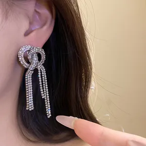 Detailed view of luxury full rhinestone bow-knot long tassel earrings worn on ear