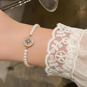 Gros plan du pendentif étoile à huit branches dorée sur un élégant bracelet en perles.