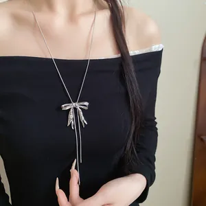 Silberne Halskette mit plissiertem Schleifenanhänger, getragen auf einem schwarzen Kleid