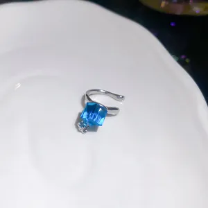 Close-up of a silver-tone ear cuff featuring a sparkling blue cubic zirconia stone