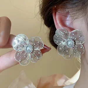 Macro view of silver hollow flower stud earrings featuring pearls and crystal accents