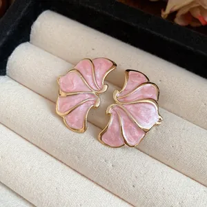 Close-up of pink enamel flower earrings with gold-tone edges in jewelry box