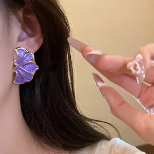 Detailed close-up of elegant vintage purple enamel flower stud earrings on model.