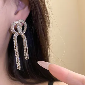 Detailed macro view of luxurious sparkling rhinestone bow earrings with long elegant tassels