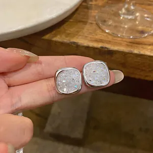 Close-up detail of elegant silver-toned square stud earrings with shimmering zirconia