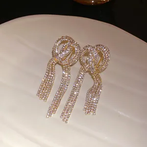 Close-up detail of brilliant full-rhinestone tassel on luxury gold-tone knot earrings