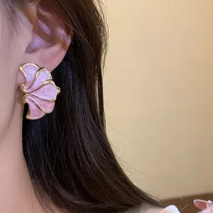 Detailed view of vintage pink enamel flower stud earrings with gold edges on model's ear