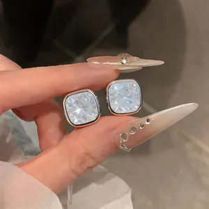 Close-up of sparkling square zircon stud earrings with silver-tone border