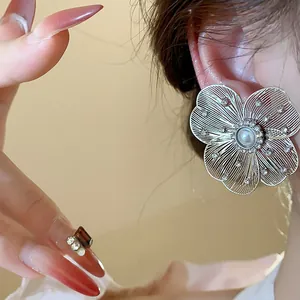 Detail view of a large silver-toned hollow floral earring with pearl and shiny crystals.
