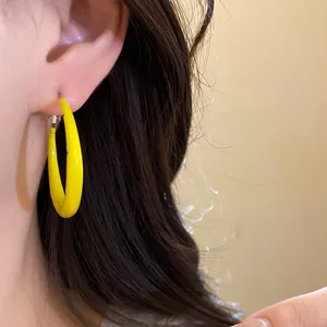 Close-up of vibrant yellow enamel C-shaped hoop earrings with blue spotted texture