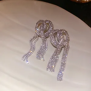Detailed close-up of luxurious full diamond bow knot earrings with long tassels