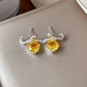 Dettaglio ravvicinato di eleganti orecchini a fiocco con zirconi gialli sfaccettati