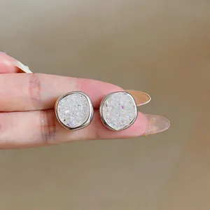 Elegant minimalist zircon stud earrings shown on finger for scale, premium silver finish.